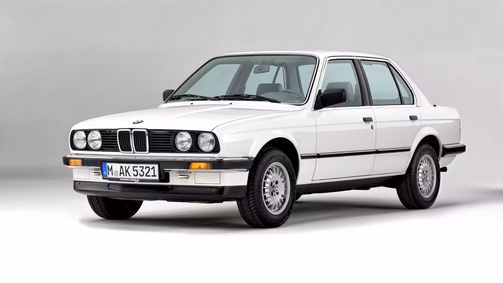 BMW 318i E30 in three-quarter view — compact, clean proportions, the shape of a car that takes driving seriously without making a performance of it