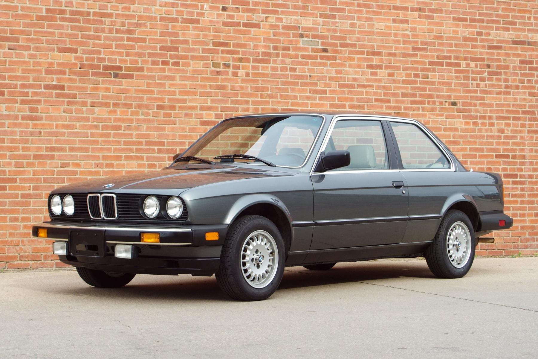 BMW 318i E30 in three-quarter view — compact, clean proportions, the shape of a car that takes driving seriously without making a performance of it