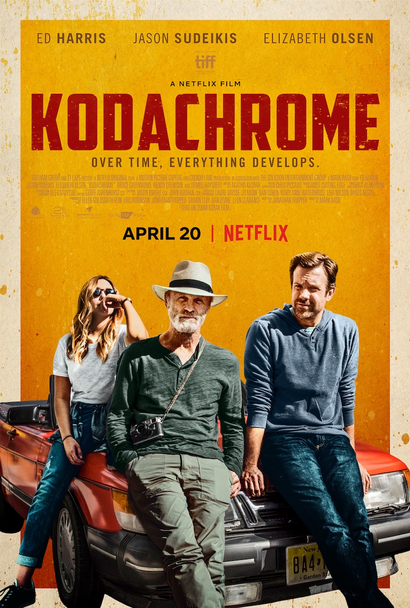 Poster for the film Kodachrome. Ed Harris, in a straw hat with a camera round his neck, leans on the bonnet of an old red convertible between Elizabeth Olsen and Jason Sudeikis, under the title and the tagline Over time, everything develops.